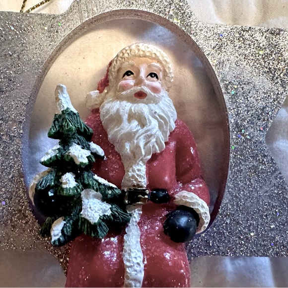 A Glittering Silver Star Christmas Ornament with a jolly Santa holding a Tree - Picture 2 of 6